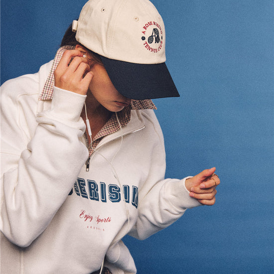 Arosris vintage-inspired two-tone cream and navy tennis club dad hat, styled with a retro half-zip sweatshirt for an effortless 90s sporty-rich aesthetic.