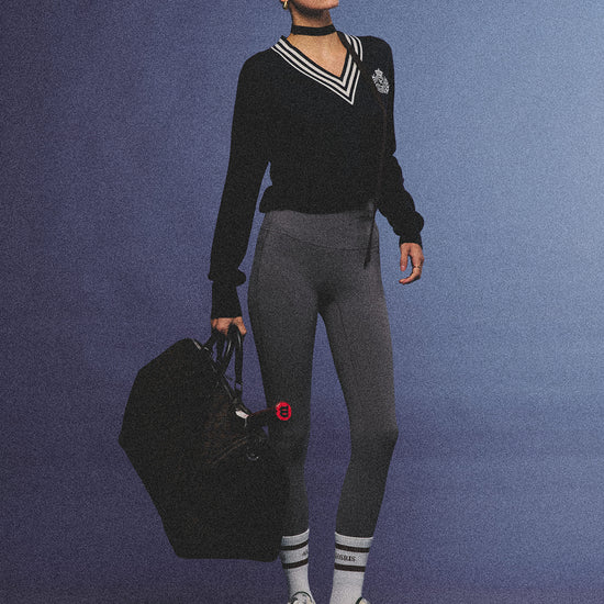 Arosris deep sapphire tennis club v-neck sweater crafted from 100% premium sheep wool, featuring contrast stripes and a vintage crest, elegantly styled on a model for an effortless 90s preppy old money and tenniscore aesthetic.