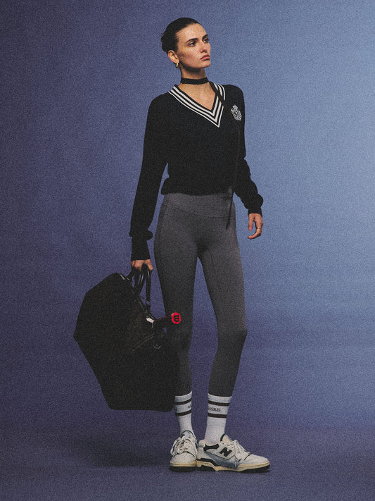 Arosris deep sapphire tennis club v-neck sweater crafted from 100% premium sheep wool, featuring contrast stripes and a vintage crest, elegantly styled on a model for an effortless 90s preppy old money and tenniscore aesthetic.